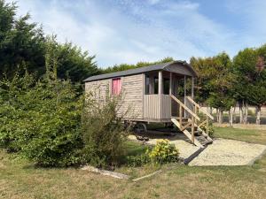 een klein huis met een veranda op een veld bij Terres du Calvados 
