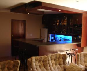 a kitchen with a bar with two chairs and a counter at Shirleys Place in Brackenfell