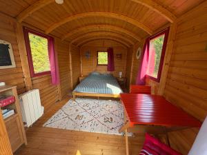 een kleine kamer met een bed in een houten hut bij Terres du Calvados 