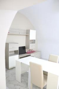 een witte keuken met een witte tafel en stoelen bij Corte Cosi&Mia Centro storico in Gallipoli +17 foto's