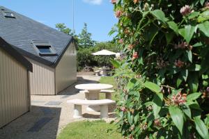 a picnic table and umbrella in a garden at Motel du Val André in Pléneuf-Val-André