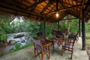 a group of chairs and tables under a pavilion next to a river at WildEscape, Yala Blocks 3, 4 & 5 in Buttala