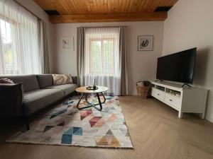 a living room with a couch and a flat screen tv at Penzion Osika in Nová Bystřice