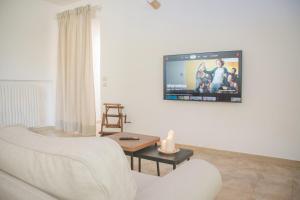 sala de estar con sofá blanco y TV en la pared en Ad un passo da Cisternino - Trulli con Camino, Foresta e BBQ, en Cisternino