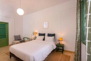 a bedroom with a large white bed and a chair at Two Bedroom Garden Cottage in Quiet Street in Limassol