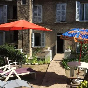 two tables and umbrellas in front of a building at Charmant studio à Néris-les-Bains 20 m² avec jardin privé in Néris-les-Bains