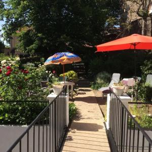 a patio with tables and umbrellas in a garden at Charmant studio à Néris-les-Bains 20 m² avec jardin privé in Néris-les-Bains