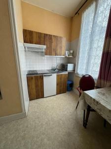 a small kitchen with wooden cabinets and a table and a window at Charmant studio à Néris-les-Bains 20 m² avec jardin privé in Néris-les-Bains