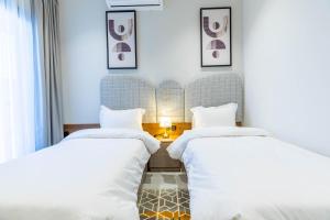zwei Betten in einem Hotelzimmer mit weißen Laken in der Unterkunft Amber Hospitality - Al Rawdah in Riad