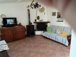 un soggiorno con un divano e una TV di Etna Evergreen Casa Vacanze a Piedimonte Etneo