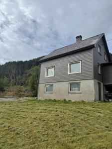 a house on a grassy field next to a house at Koselig hus i landlige omgivelser in Tysnes