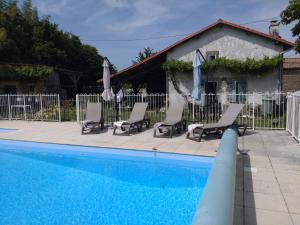 a pool with chairs and umbrellas next to a fence at B&B Franglaise in Romagne