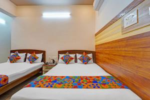 a bedroom with two beds and a wooden headboard at FabHotel Raja Residency in Alāndurai