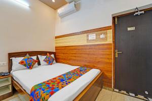 a bedroom with a bed and a wooden door at FabHotel Raja Residency in Alāndurai