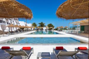 a swimming pool with chairs and umbrellas at Sol Fuerteventura Jandia - All Suites in Morro del Jable
