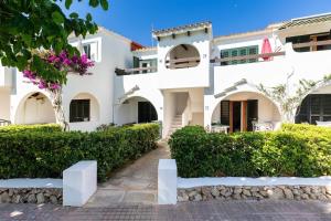 a large white building with bushes in front of it at Your new corner in Menorca in Arenal d'en Castell