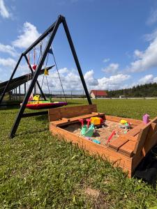 a sandbox in the grass next to a swing at Wzgórze nad Jeziorem Blanki in Żegoty