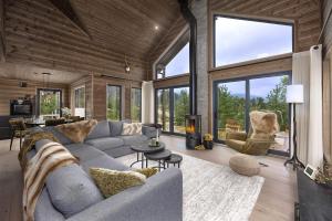 a living room with a gray couch and chairs and windows at Saga Hytte | 6p | With Sauna, Hot Tub & Water View in Sinnes