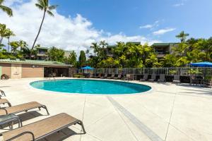a swimming pool with benches and tables and palm trees at Incredible Ocean Views in Kailua-Kona