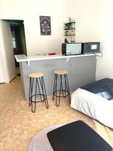 サン・ジュニアンにあるStudio meublé centre-ville Saint Junienのカウンターと椅子2脚、ベッドのある部屋