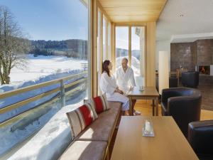 a man and woman sitting in a room with a window at derWaldfrieden naturparkhotel in Herrenschwand +31 photos