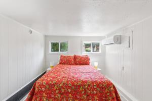 a bedroom with a red bed with two windows at Dave's Last Resort Lakeside-Comfy Cabin 5 Hotel Room in Monticello
