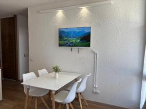 a white dining room table with white chairs and a tv at Terrazza sul Brenta - Monte Bondone TN in Vason