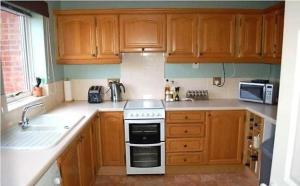 a kitchen with wooden cabinets and a stove top oven at Shared Double Rooms in Buckinghamshire