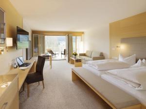 a hotel room with a large bed and a desk at derWaldfrieden naturparkhotel in Herrenschwand +31 photos