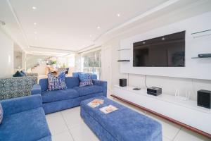a living room with blue couches and a tv at 122 Camarque-Lavish lookout Penthouse in Umdloti