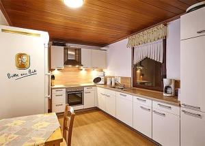 cocina con armarios blancos, mesa y comedor en Ferienhaus Für 11 Personen Und 1 Kind, en Birresborn