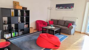 Una sala de estar con un sofá, una mesa y sillas rojas. en Spacious Ferienwohnung nähe KOB Uni, 