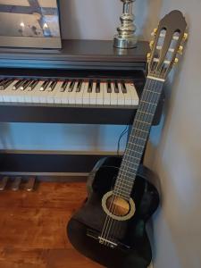 ナジュマロシュにあるFecskefészek vendégházのピアノの横に座るギター