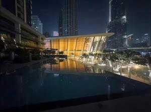 a building with a pool in a city at night at Grande Downtown Dubai Luxury 2BR Apt with Burj Khalifa & Dubai Fountain Views in Dubai