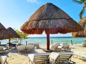 a beach with chairs and umbrellas and the ocean at Grand Sunset Princess - All Inclusive in Playa del Carmen