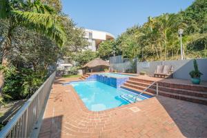 a swimming pool with a brick walkway next to a fence at 122 Camarque-Lavish lookout Penthouse in Umdloti