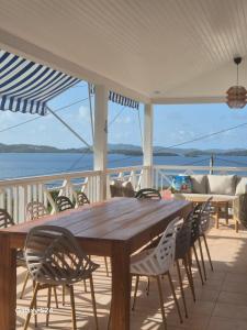 a wooden table and chairs on a porch with a view of the water at Beautiful sea view building in Le Robert