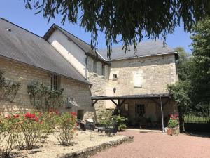 an old stone building with a courtyard with flowers at Riverside Hideaway in Cinais in La Roche-Clermault