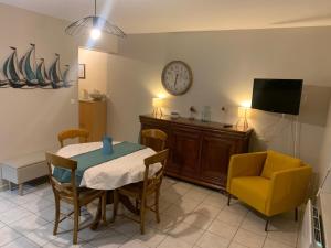 a dining room with a table and a chair and a clock at Maison duplex centre plage port cabine in Le Crotoy
