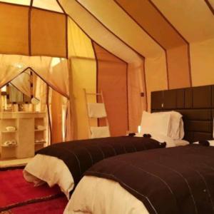 a bedroom with two beds in a tent at Merzouga tente luxury in Merzouga