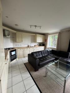 a living room with a black couch in a kitchen at Spacious Two Bedroom Apartment in Bracknell in Bracknell +3 photos