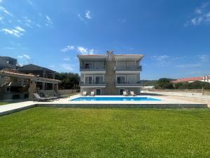 a large house with a swimming pool in front of it at Costa Kalamos Suites in Kalamos