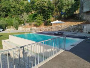 a swimming pool with a deck and an umbrella at Várzeas Nature House in Soengas