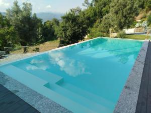 a pool with blue water and trees in the background at Várzeas Nature House in Soengas
