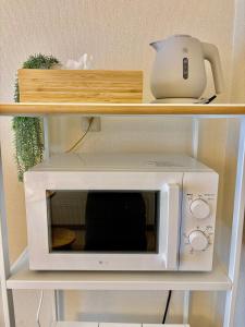 a microwave on a shelf with a tea pot on it at Hachioji House 206 Apartment in Hachioji +21 photos