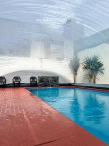 - une piscine avec 2 chaises à côté d'un bâtiment dans l'établissement Nuevo Hotel Córdoba, à Villa Carlos Paz