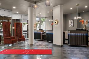 a lobby with chairs and tables and a red rug at Leonardo Hotel Mainz in Mainz