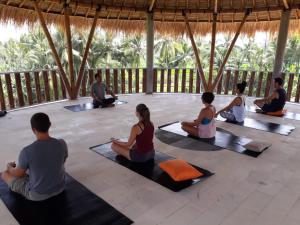 un grupo de personas sentadas en una clase de yoga en Coco Verde Bali Resort, en Tanah Lot
