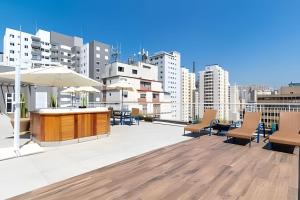 eine Dachterrasse mit Stühlen und einem Sonnenschirm in der Unterkunft You Link Paulista - Ap com Jacúzzi próx. à Liberdade in São Paulo