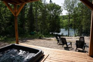Un jacuzzi sentado en una terraza con dos sillas. en Spa and Lakefront - Oasis des chutes, en Lac-Saint-Paul